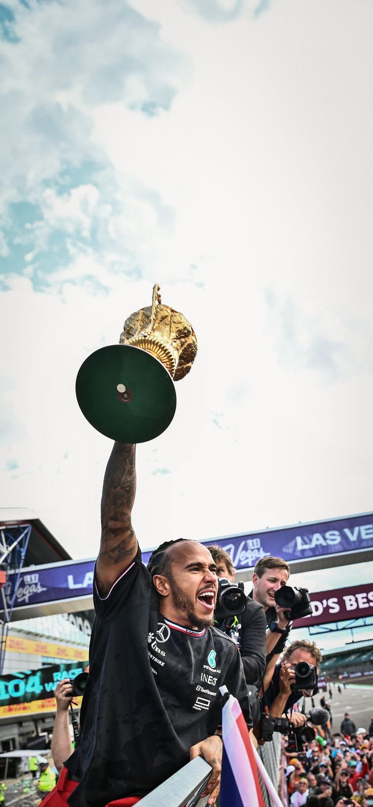 a man holding up a trophy in the air with other people around him and onlookers behind him