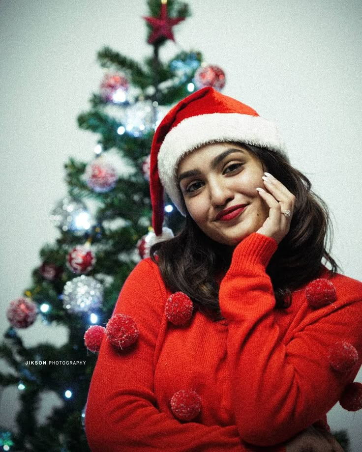 a woman in a santa hat talking on her cell phone next to a christmas tree