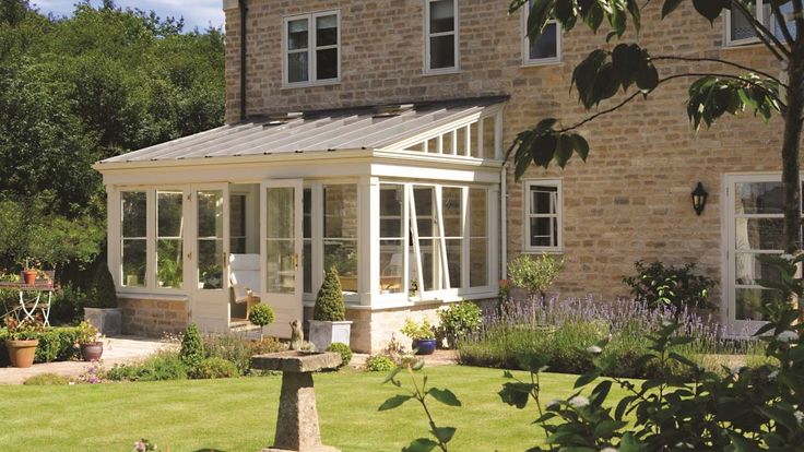 a house with a garden in front of it and lots of windows on the side