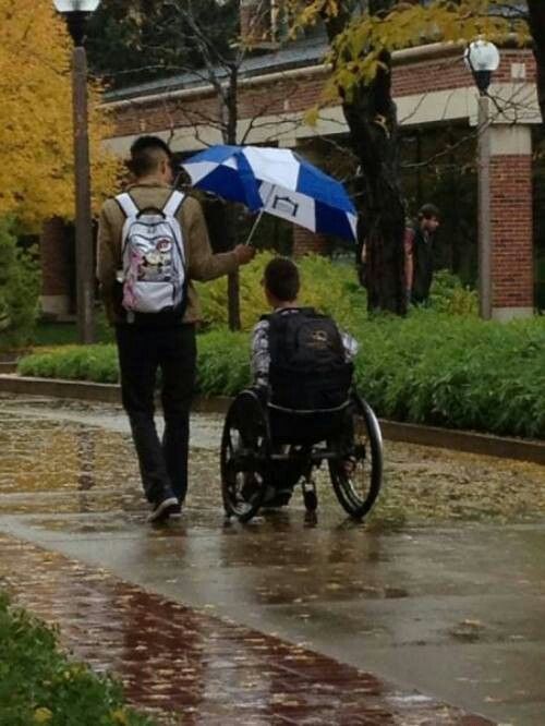 a man in a wheel chair is walking with an umbrella over his head and another person behind him