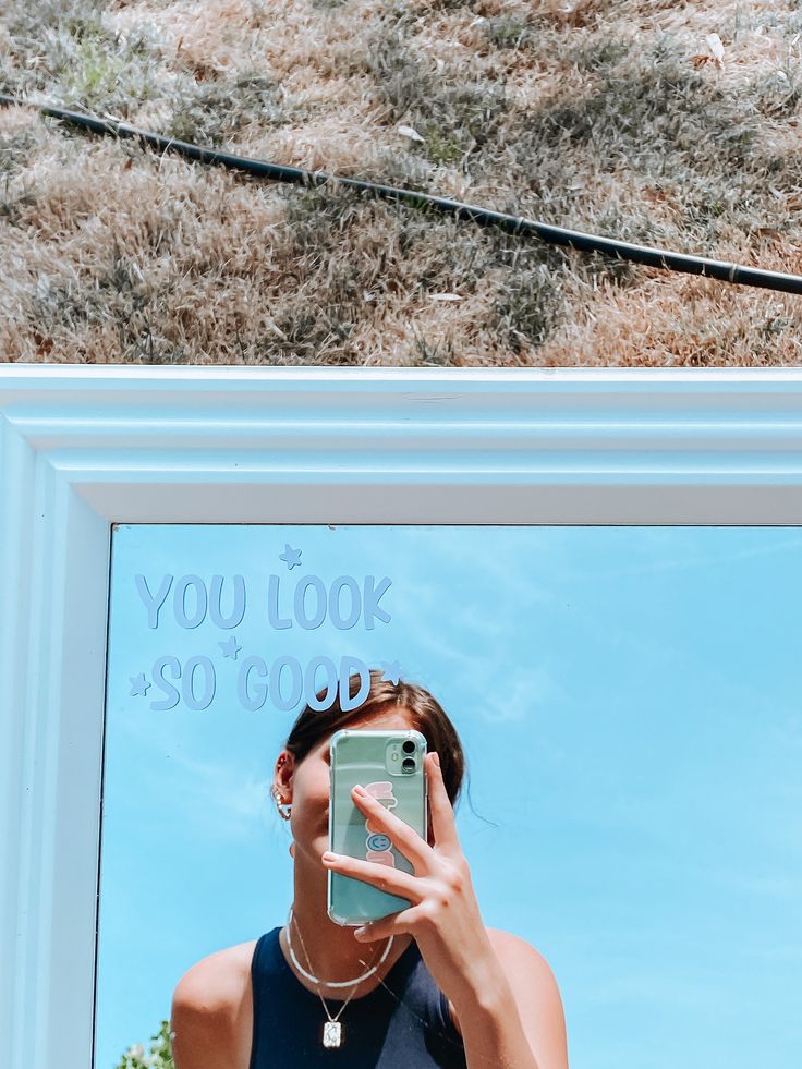 a woman taking a selfie in front of a mirror with the words you look $ 50 good written on it