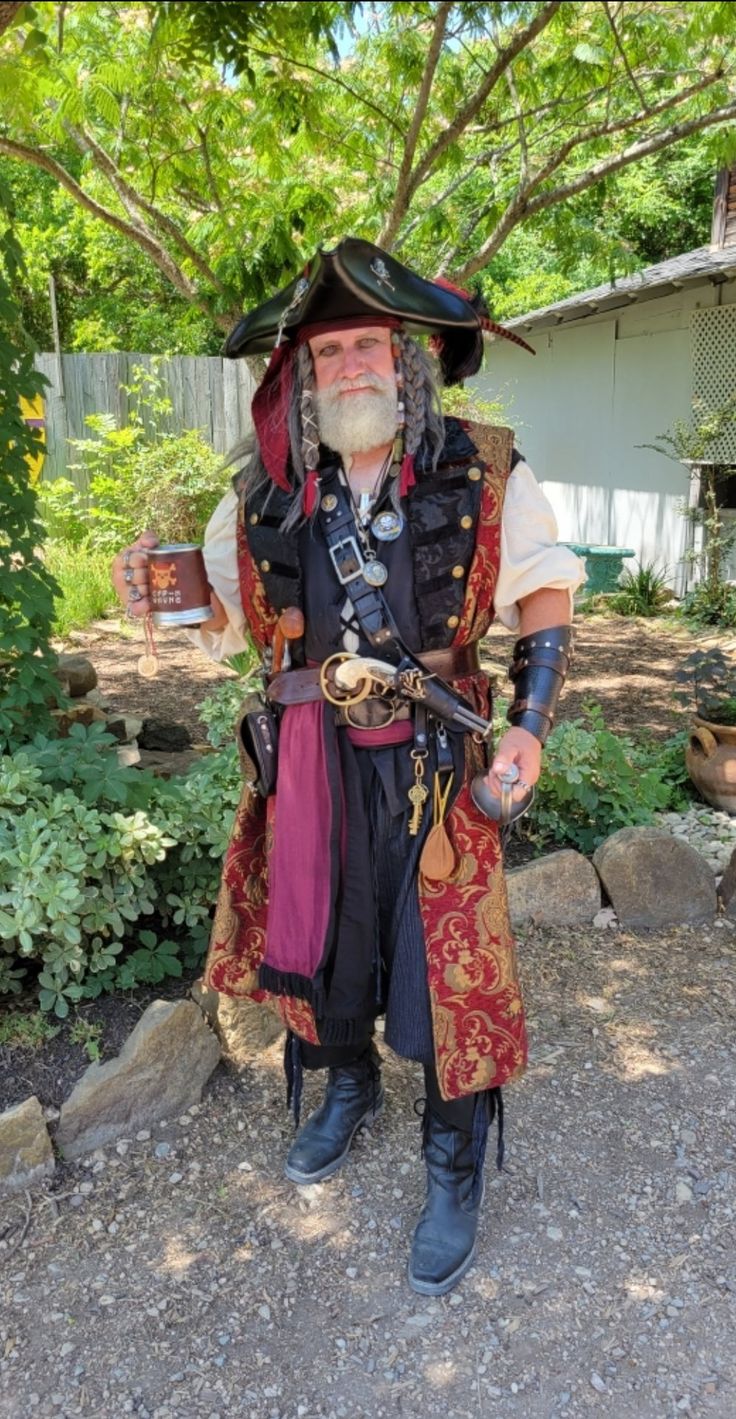 a man dressed up in pirate costume standing on the ground with his hands behind his back