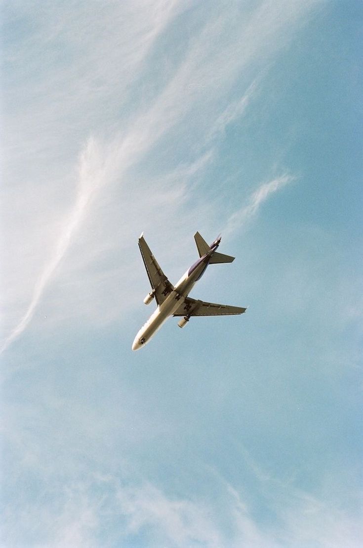 an airplane is flying in the sky on a clear day with some wispy clouds