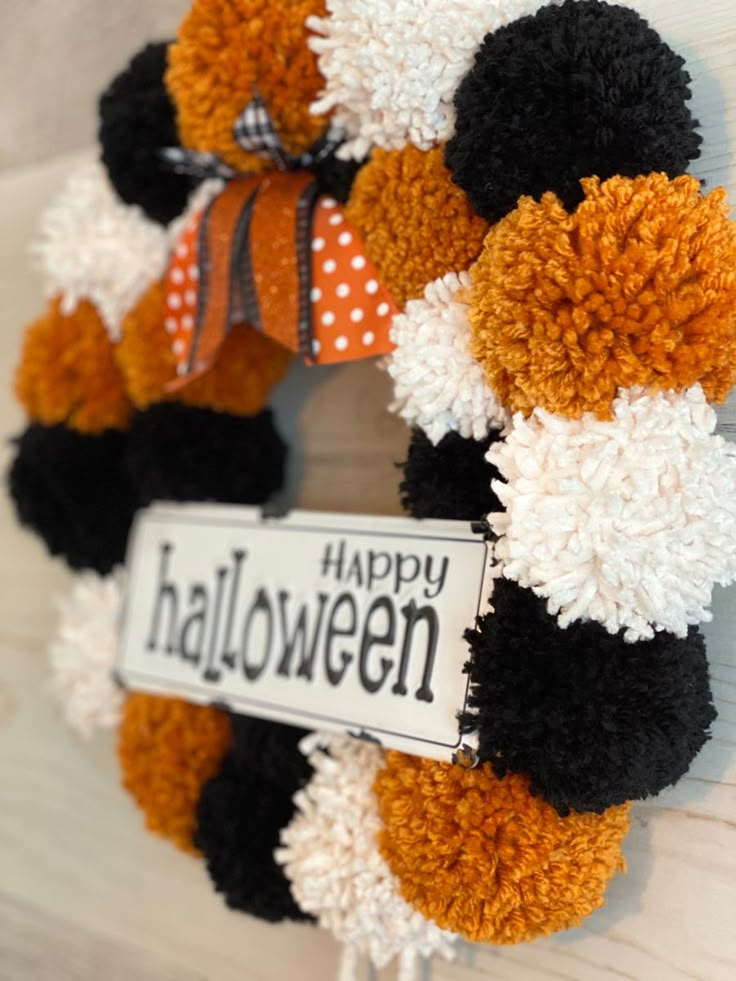 a halloween wreath with pom - poms and a happy sign hanging on the front door