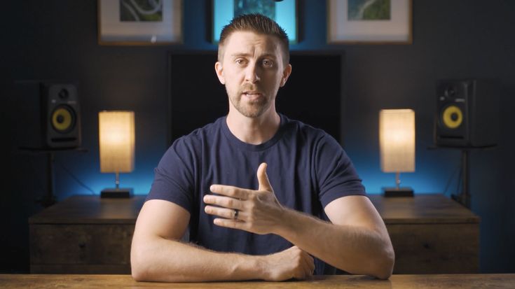 a man is sitting at a table with his hands crossed and looking to the side