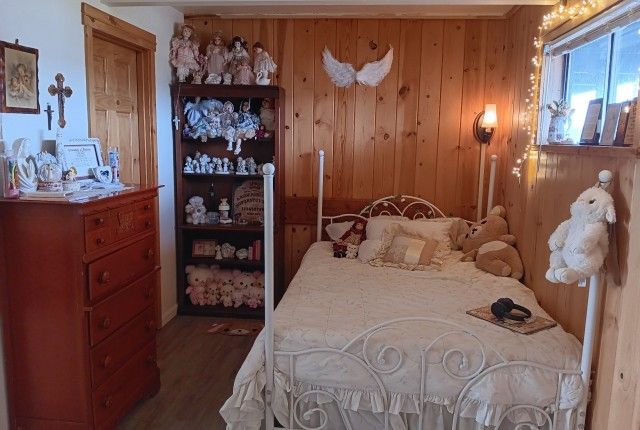 a bed room with a neatly made bed next to a dresser and shelves filled with stuffed animals