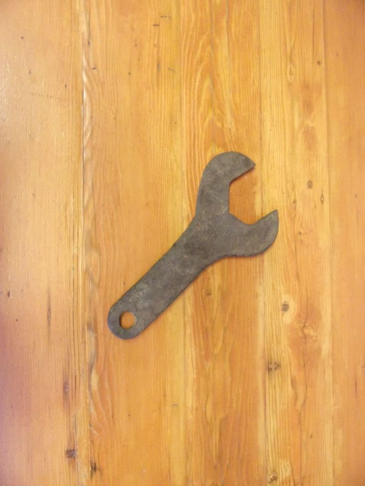 an old wrench sitting on top of a wooden table