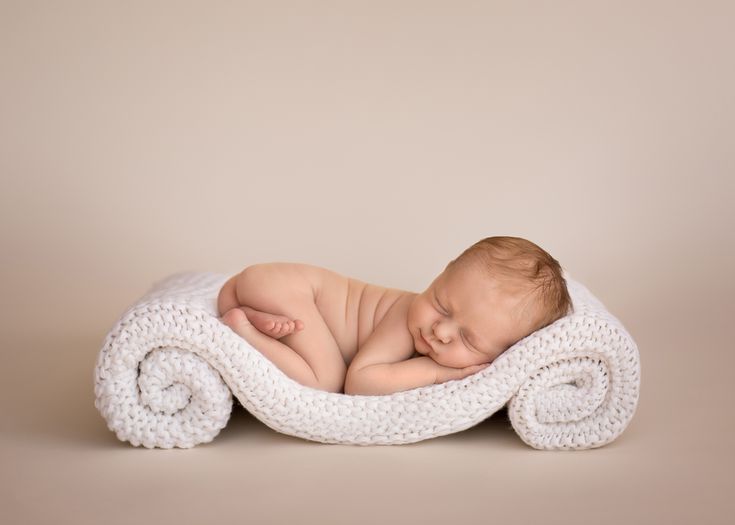 a newborn baby is sleeping on a white blanket and wrapped in a crochet