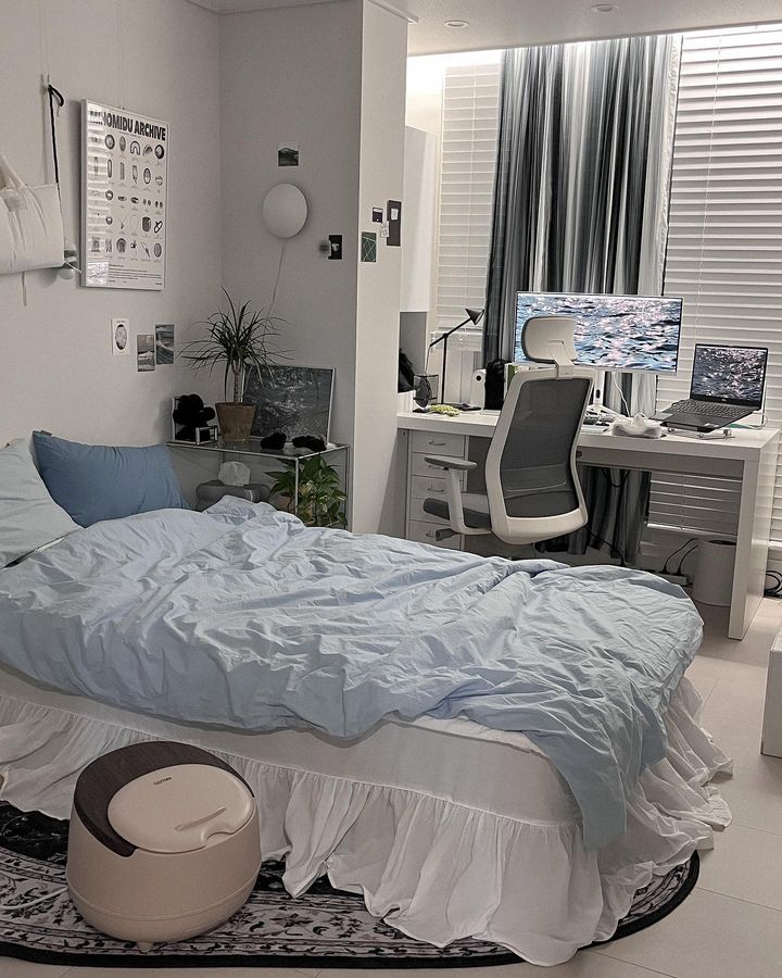 a bedroom with a bed, desk and computer monitor on the wall next to it