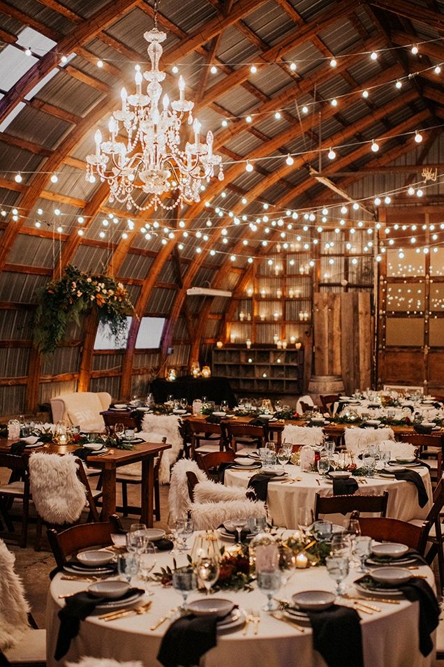 the inside of a barn with tables and chairs set up for an elegant wedding reception