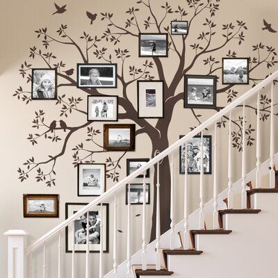 a tree with pictures on it and stairs in front of the bannister wall