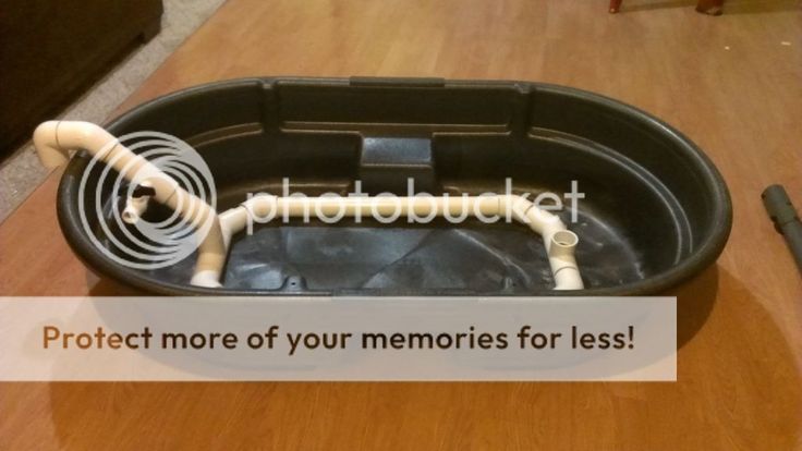 a black container with pipes in it on top of a wooden table