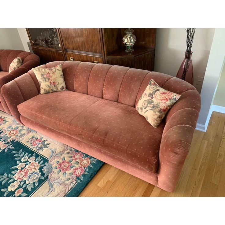 a pink couch sitting on top of a hard wood floor next to a wooden dresser