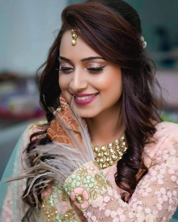 a woman with long hair wearing a pink dress and gold jewelry is smiling at the camera