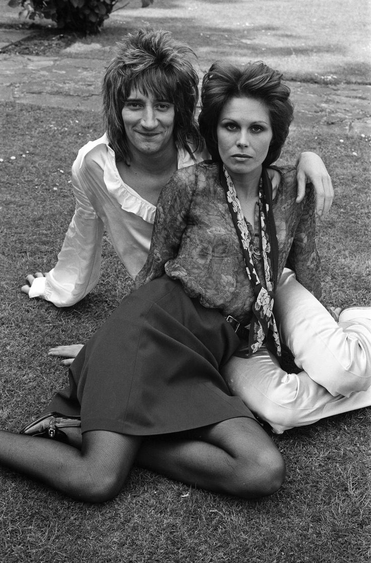 two women are sitting on the ground posing for a black and white photo with their arms around each other