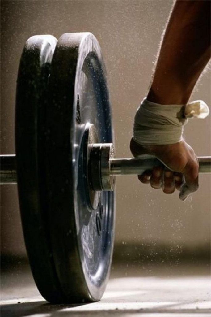 a close up of a person holding a barbell with bandages on their wrists and feet