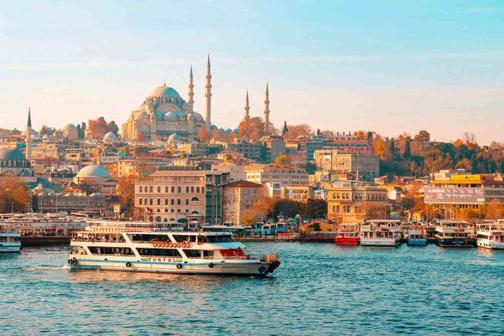 several boats floating on the water in front of a large city with many spires