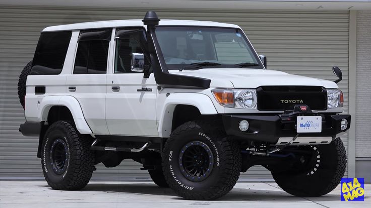 a white four door suv parked in front of a garage