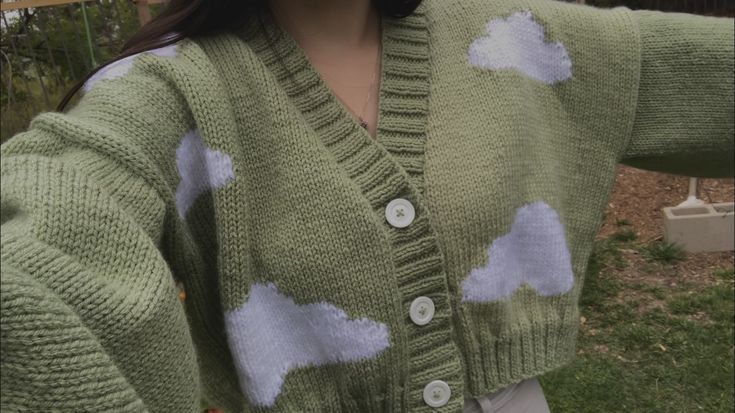 a woman wearing a green cardigan with white clouds on the front and back buttons