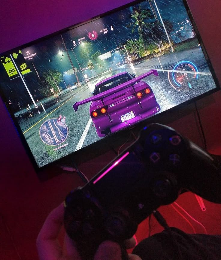 a person holding a video game controller in front of a tv screen with the image of a purple car on it