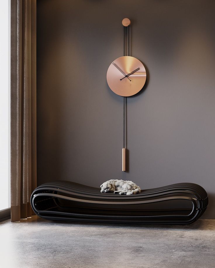 a dog laying on top of a black couch in front of a wall mounted clock