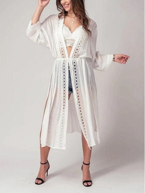 Add a touch of boho chic to your wardrobe with this kimono style cardigan. The front lace detail adds a touch of femininity and the long, flowy fit is perfect for a day at the beach or pool. This versatile piece can be worn as a cover up for your swimsuit, or as a festive addition to your outfit for a spring or summer party. Take it on your next resort vacation for a touch of bohemian flair. This kimono cardigan is the ultimate beach boho accessory Small (2/4), Medium (6/8), Large (10) Maxi Card Bohemian Lace Patchwork Summer Cover-up, Spring Beach Party Cover-up With Crochet Trim, Chic Lace Cover-up For Beach Season, Spring Festival Lace Cover-up, Lace Open Front Cover-up For Summer, Flowy V-neck Cardigan For The Beach, Chic V-neck Festival Cover-up, Bohemian Spring Brunch Cover-up, Chic Lace Trim Beach Cover-up