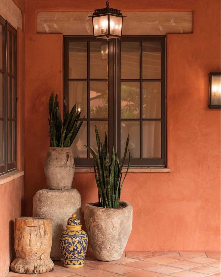 three potted plants sitting on top of each other in front of a window next to two vases