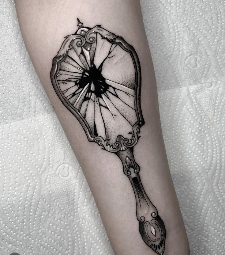 a black and white photo of a fan tattoo on the leg