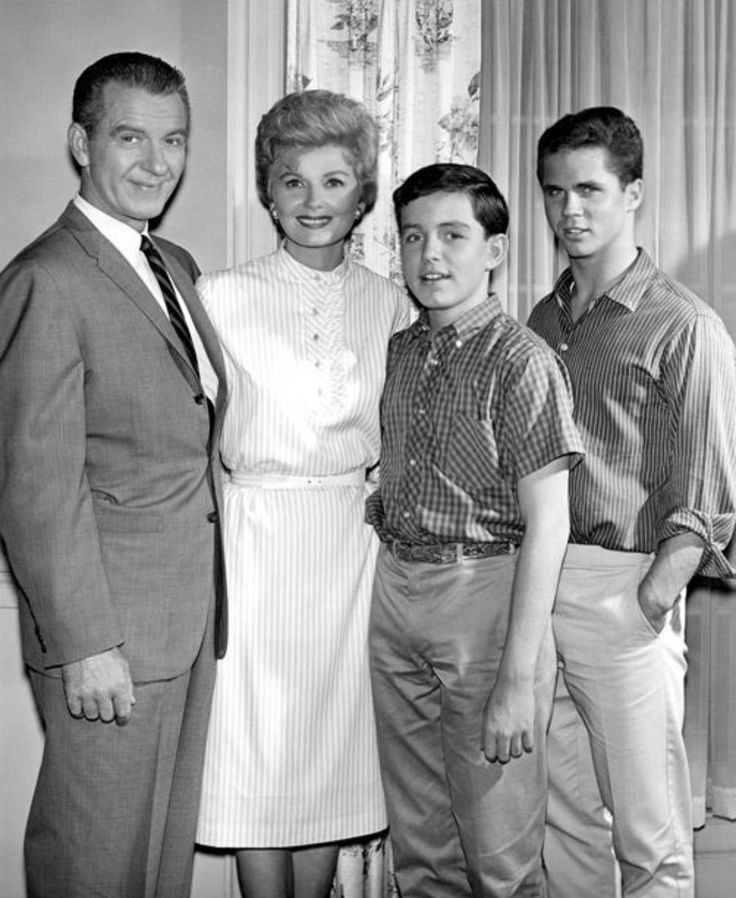 a black and white photo of three people standing next to each other in front of a window