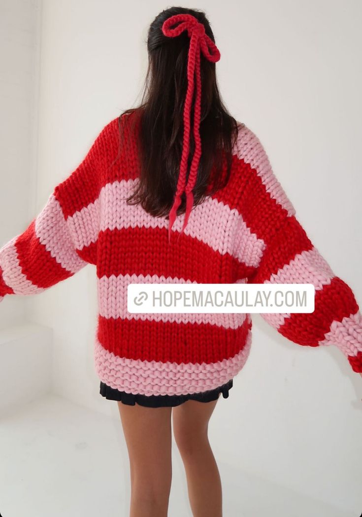 a woman wearing a red and white striped sweater is standing in front of a wall