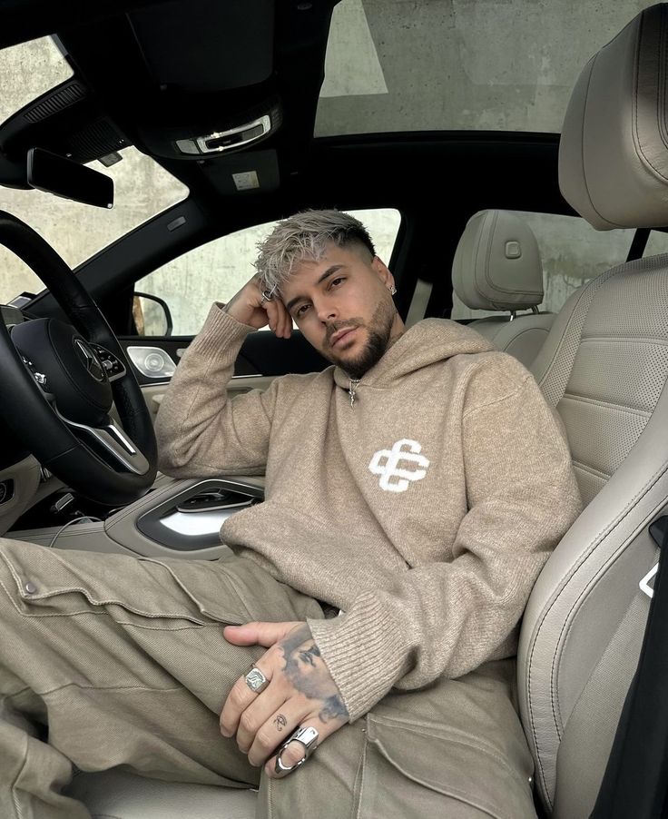 a man sitting in the driver's seat of a car talking on a cell phone