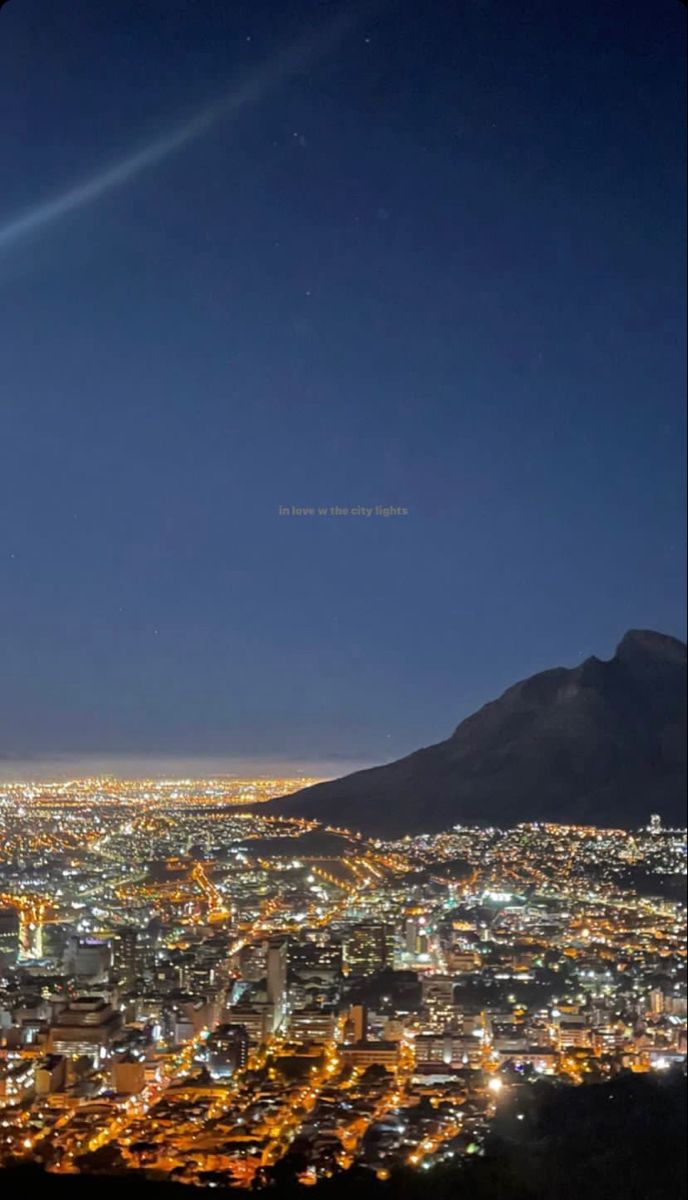 the city lights shine brightly in the night sky as seen from an observation point on top of a mountain