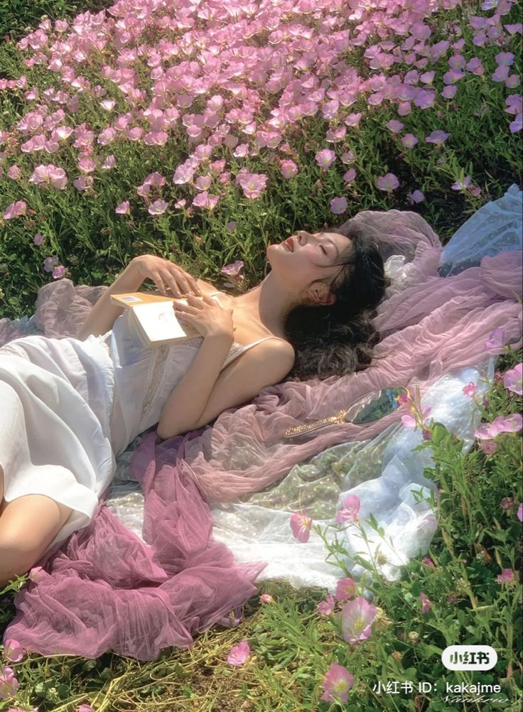 a woman laying on top of a field of flowers