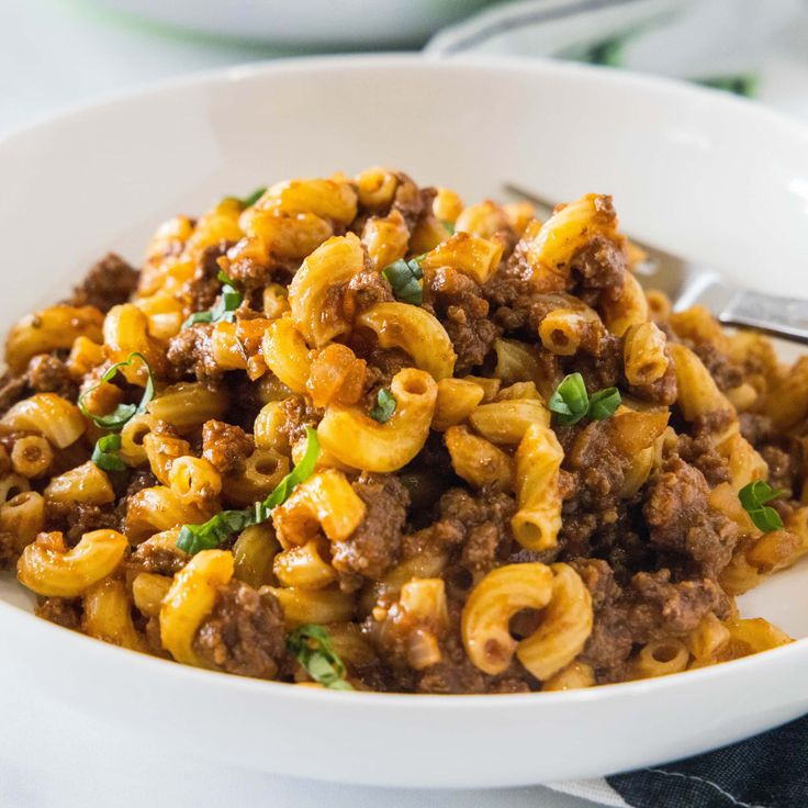 a white bowl filled with pasta and meat