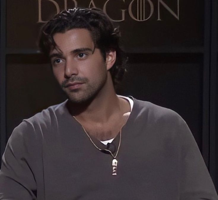 a man sitting down in front of a black wall with the words dragon on it