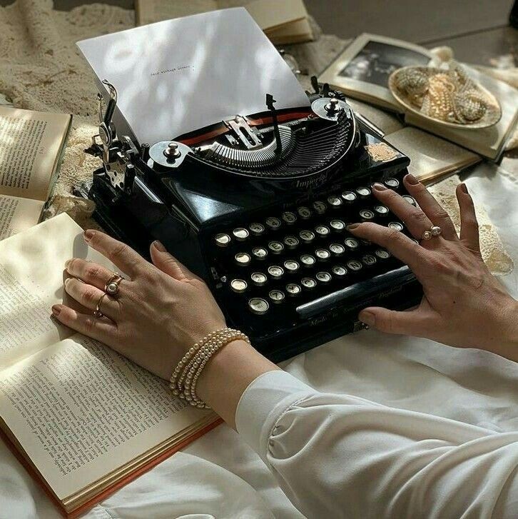 a woman typing on an old fashioned typewriter with her hands resting on the book