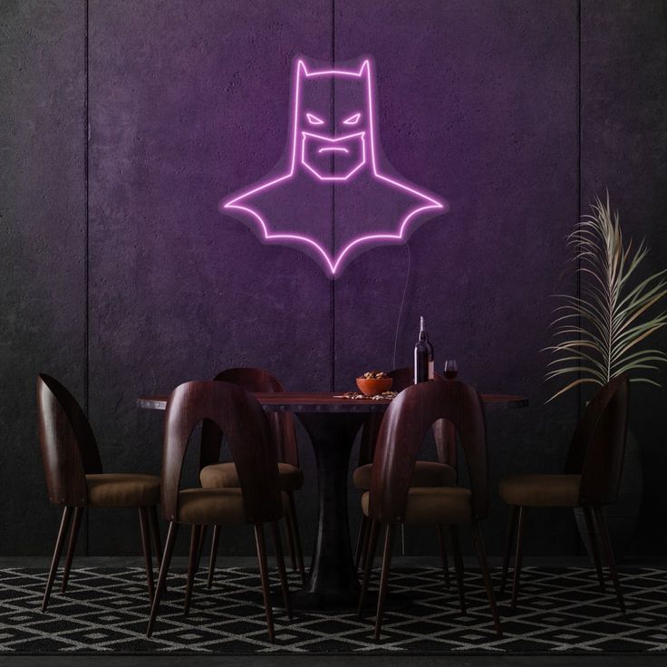 a purple neon batman sign on the wall above a dining room table with four chairs