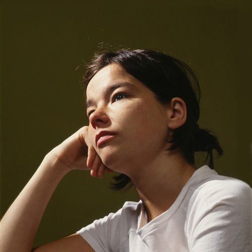 a woman sitting down with her hand on her chin and looking off to the side