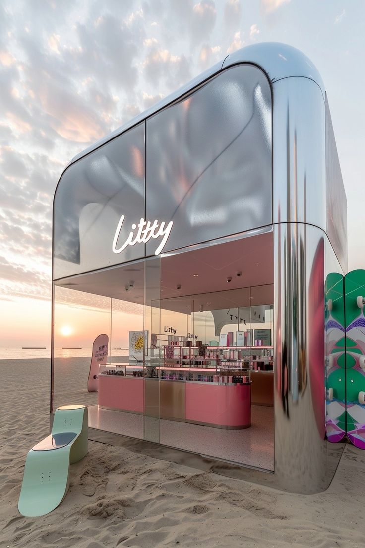 the exterior of an ice cream shop on the beach at sunset, with pink and green surfboards behind it