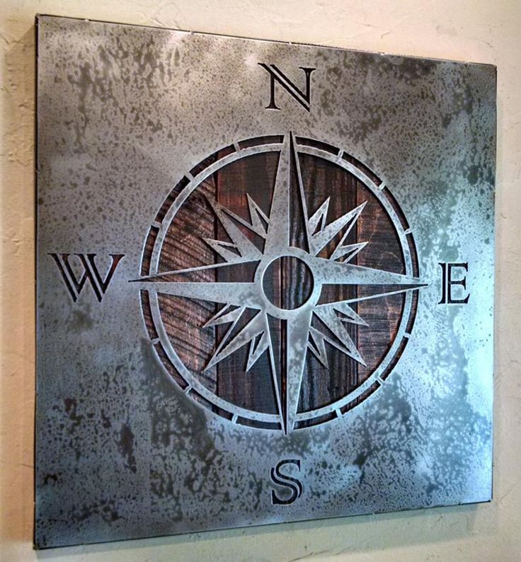 a metal and wood sign with a compass on it's side hanging on a wall