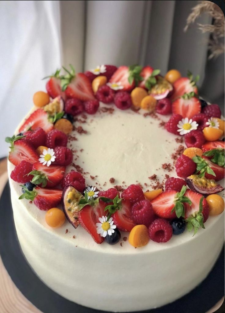 a white cake topped with fresh fruit and flowers