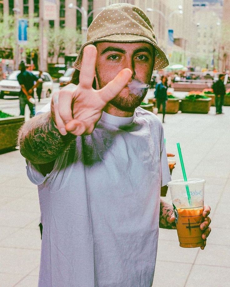 a man making the peace sign while holding a drink