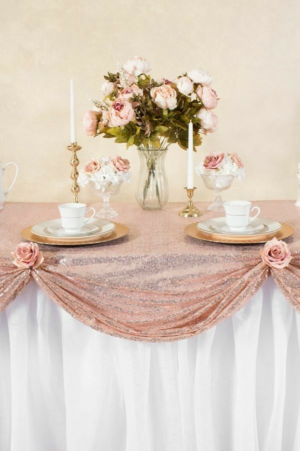 the table is set with pink flowers and tea cups