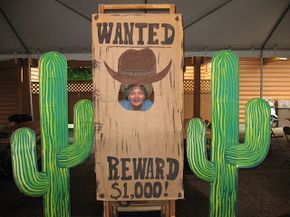 a cardboard sign that says wanted reward $ 1, 000 in front of a cactus