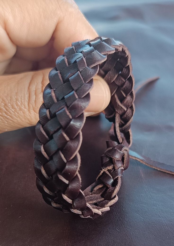 a person holding onto a piece of leather that has been braided into an ornament