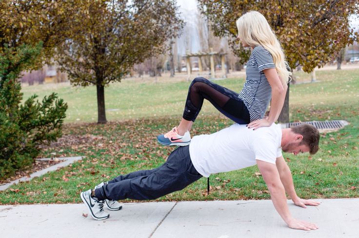 a man and woman doing push ups on their skateboards in front of some trees