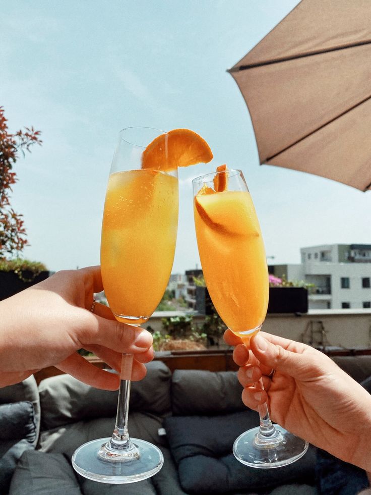 two people toasting with orange juice and an umbrella