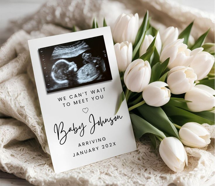 a baby announcement with tulips in front of it and a card that says, we can't wait to meet you