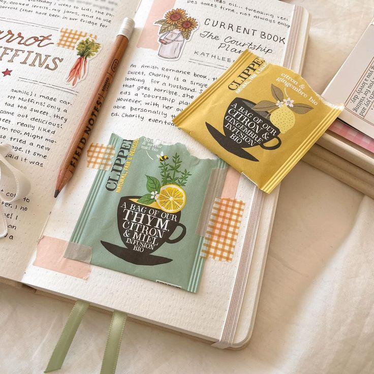 an open book on top of a table next to a cup of coffee and a pen