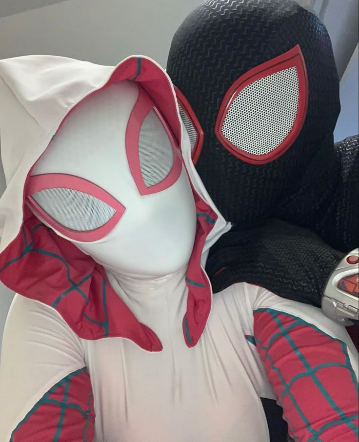 a person wearing a spider man costume next to a stuffed animal with a cell phone in his hand